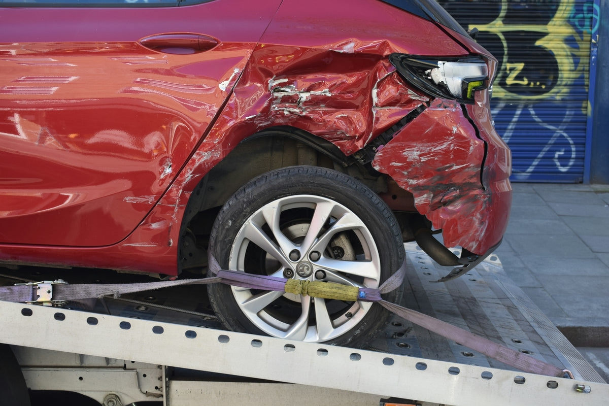 Crashed red car on a flatbed tow truck